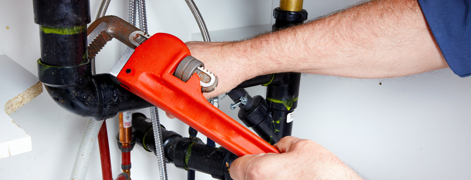 Plumber tightening pipe with wrench
